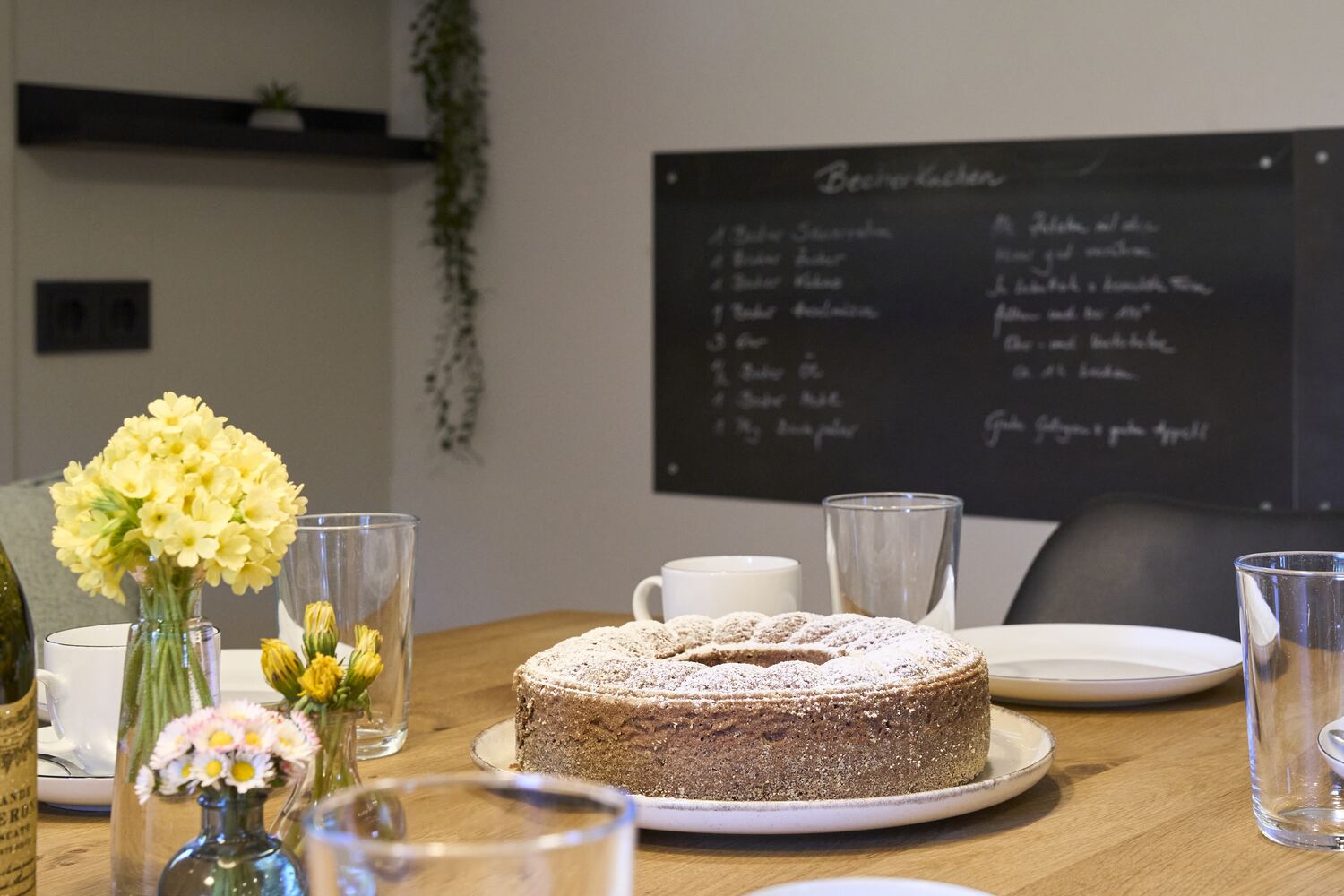 Selbstgebackener Kuchen und Frühlingsblumen auf dem Esstisch