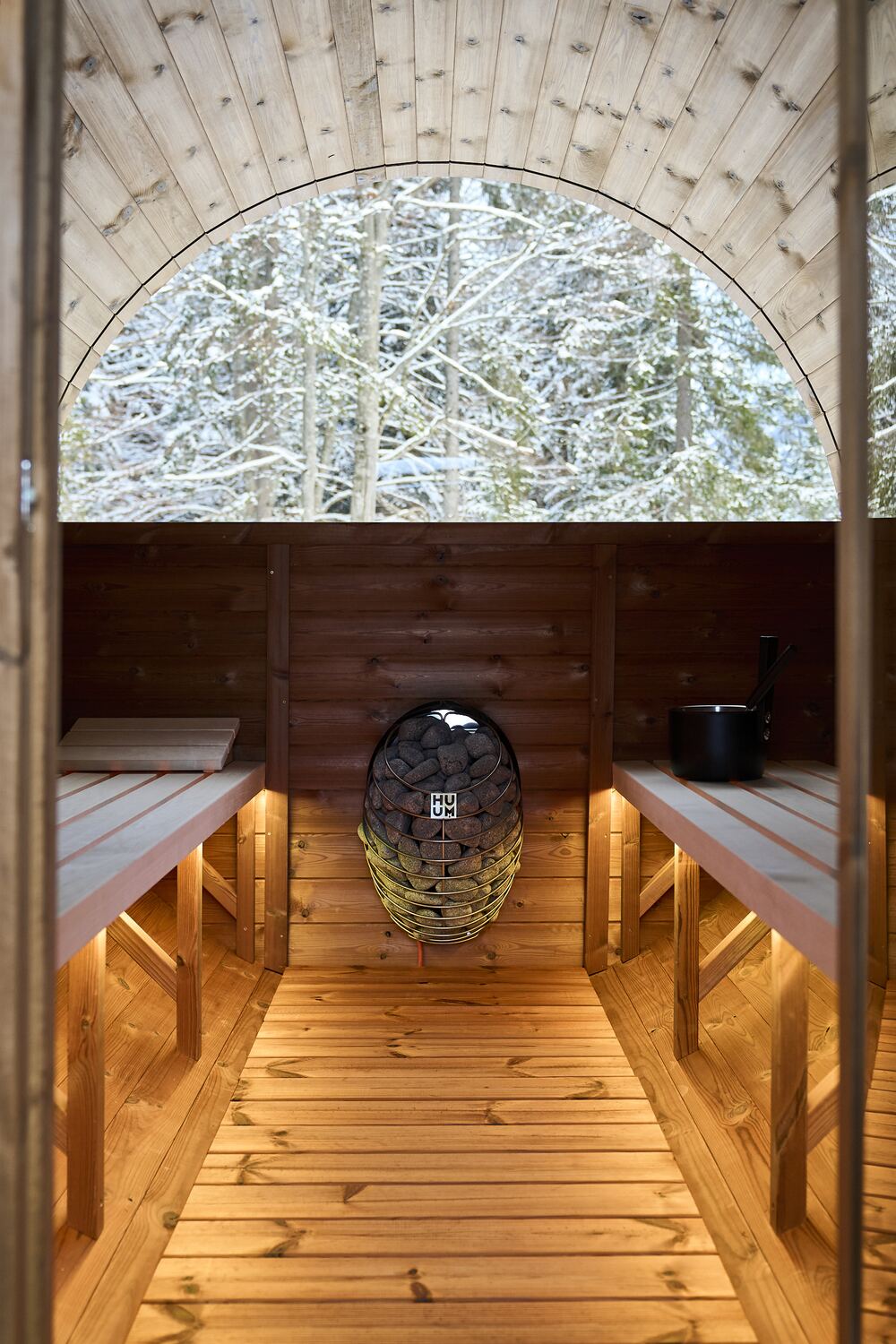 Blick aus der Fass-Sauna durch das Rundfenster in den Winterwald