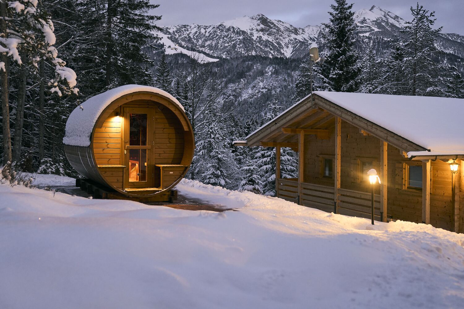 Fass-Sauna und Chalet im Abendlicht mit Blick auf die Berge