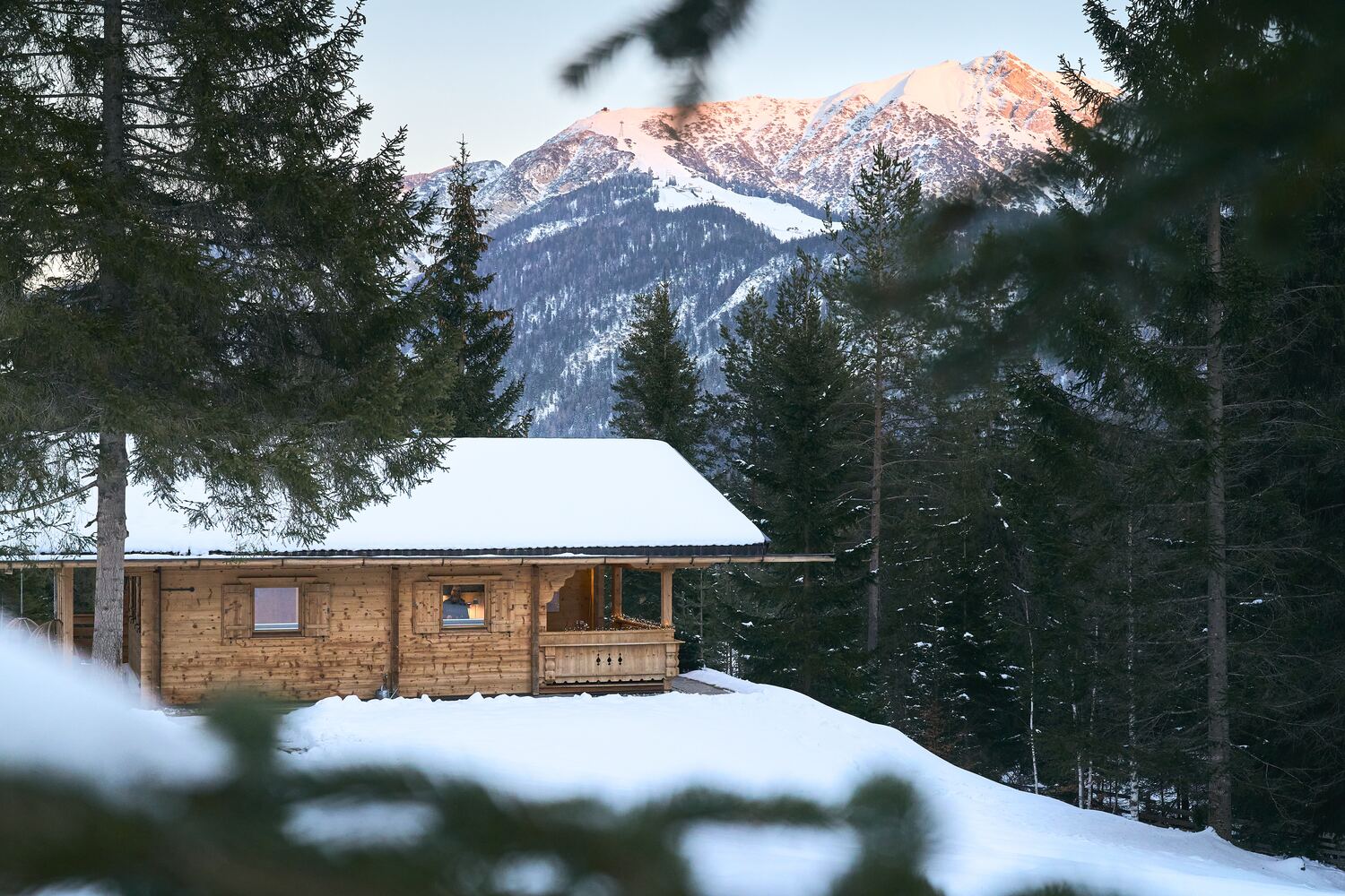 Das verschneite Chalet am Waldrand, dahinter die Seefelder Berge im Alpenglühen