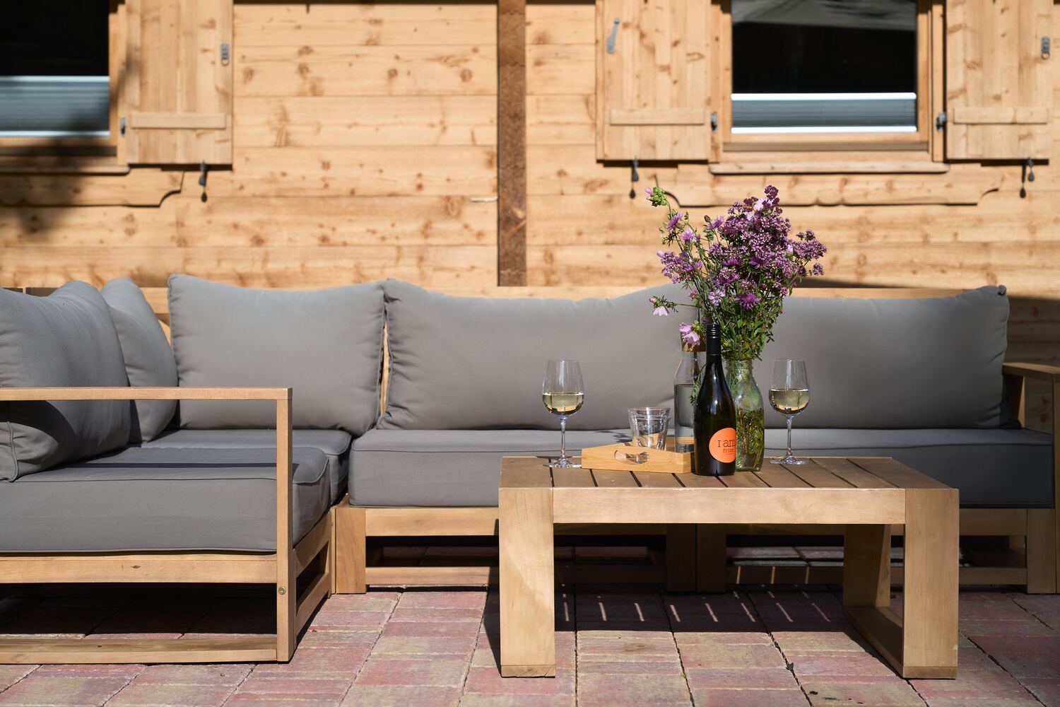 Lounge-Ecke auf der Terrasse mit Wein und Wiesenblumen