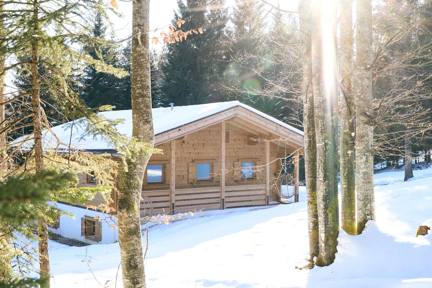 Wintersonne über dem verschneiten Chalet im Wald